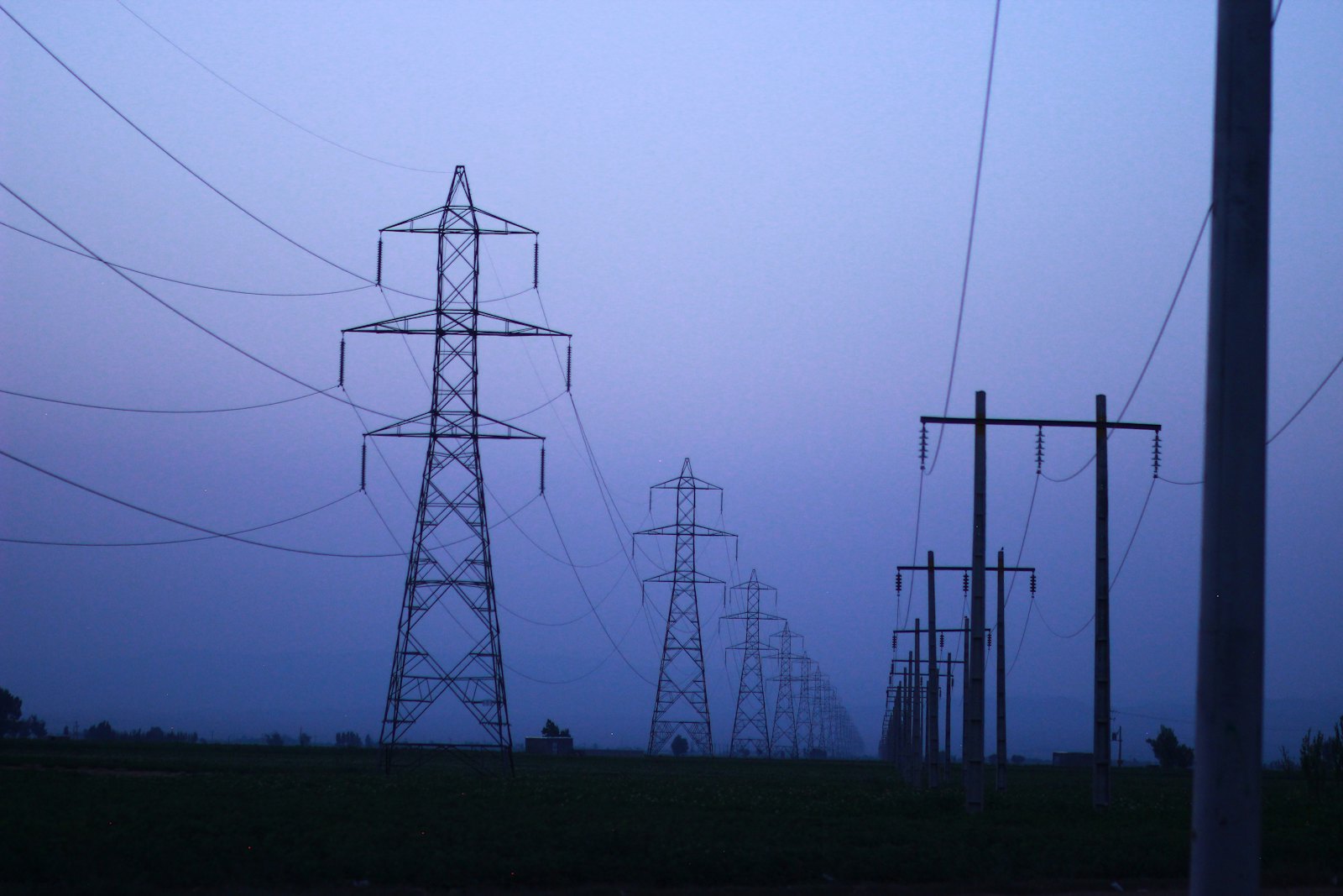 Torres de transmisión eléctrica en la niebla al anochecer